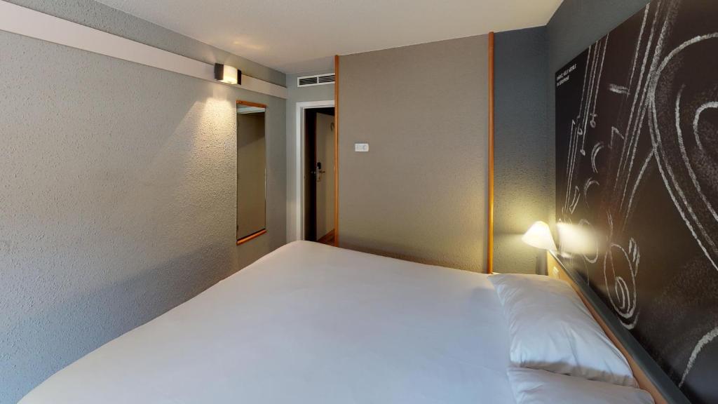 a bedroom with a large white bed in a room at ibis Dinant Centre in Dinant
