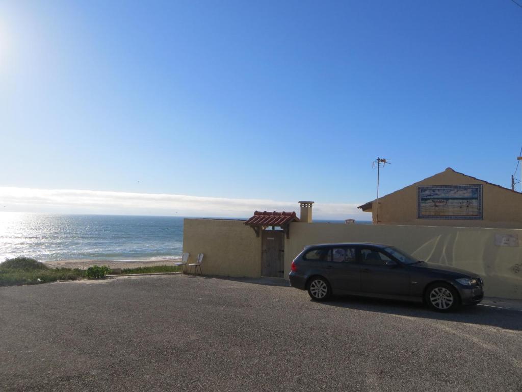 a car parked next to a building next to the ocean at Dream House On The Beach in Figueira da Foz