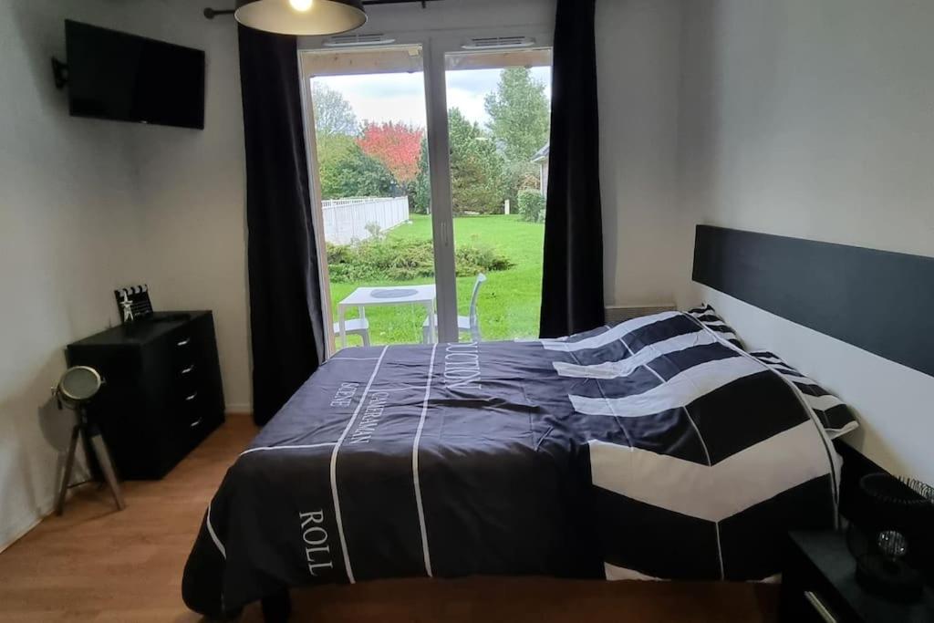 Un dormitorio con una cama y una ventana grande. en Studio avec piscine près d&#39;Honfleur, en Équemauville