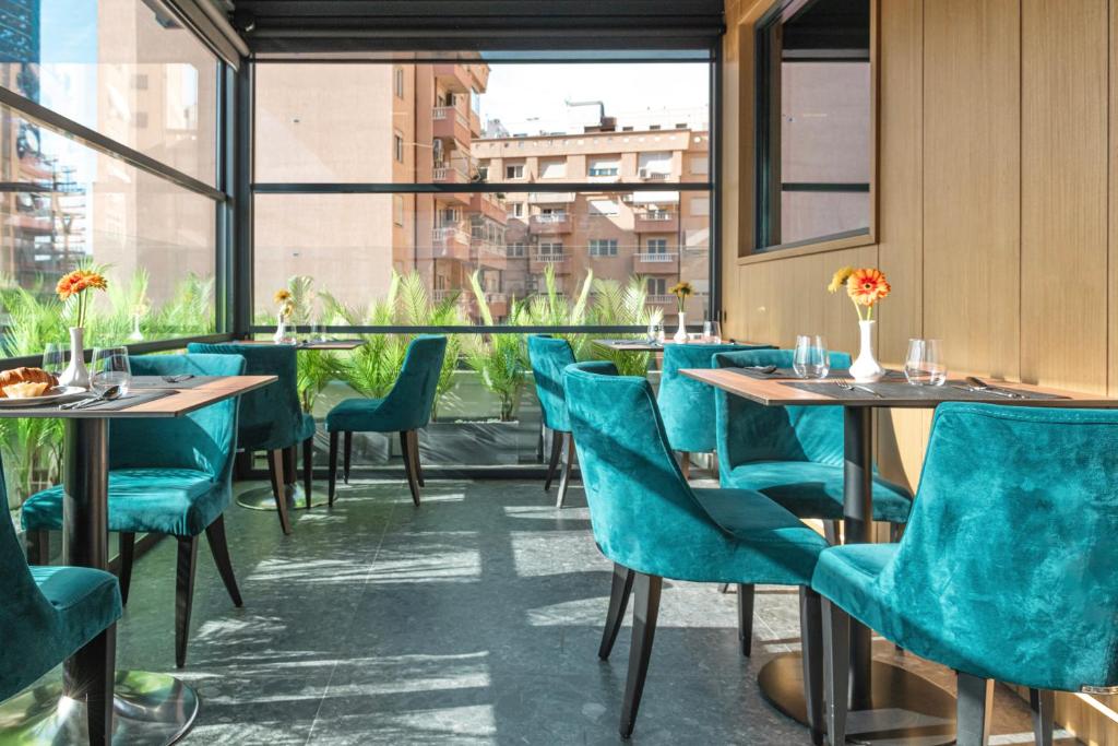 un ristorante con sedie e tavoli blu e una finestra di Central Inn Hotel a Tirana