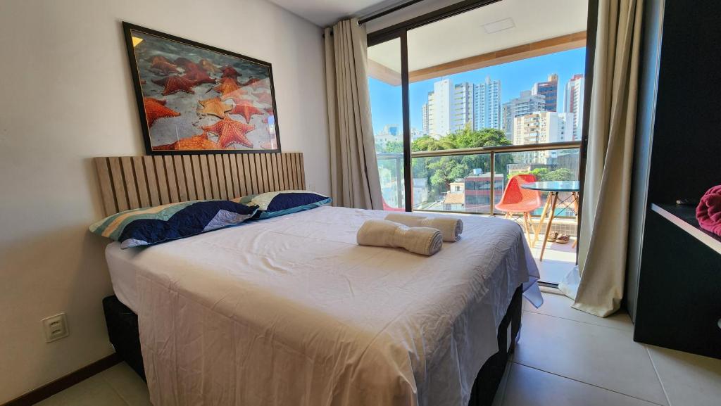 um quarto com uma cama e uma grande janela em Barra Stella do Mar Studio em Salvador