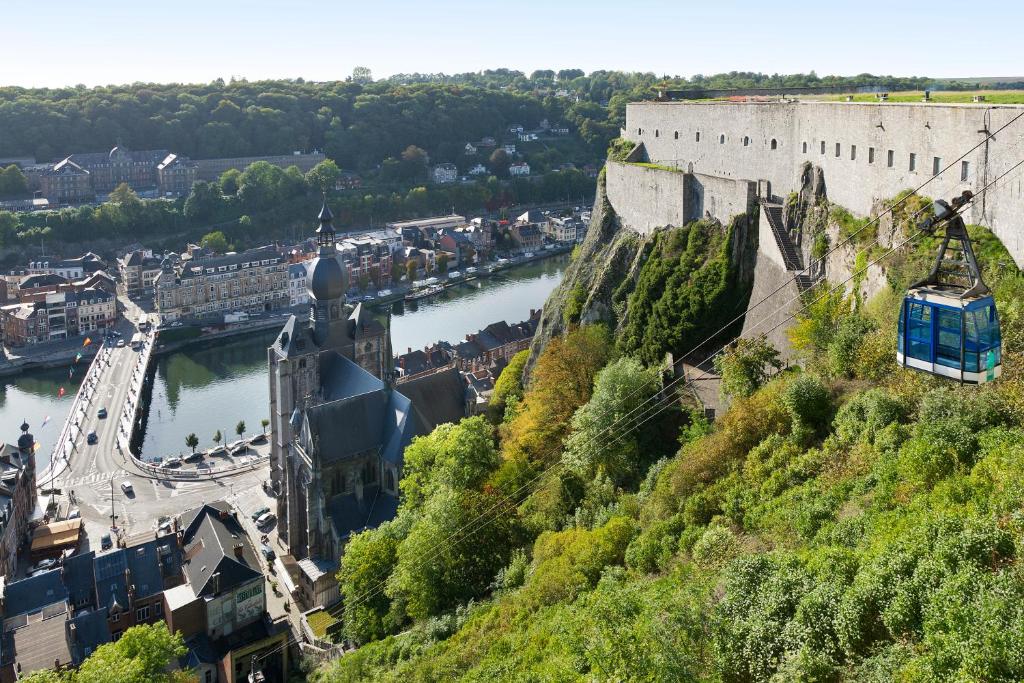 a tram on a hill next to a castle and a river at ibis Dinant Centre in Dinant