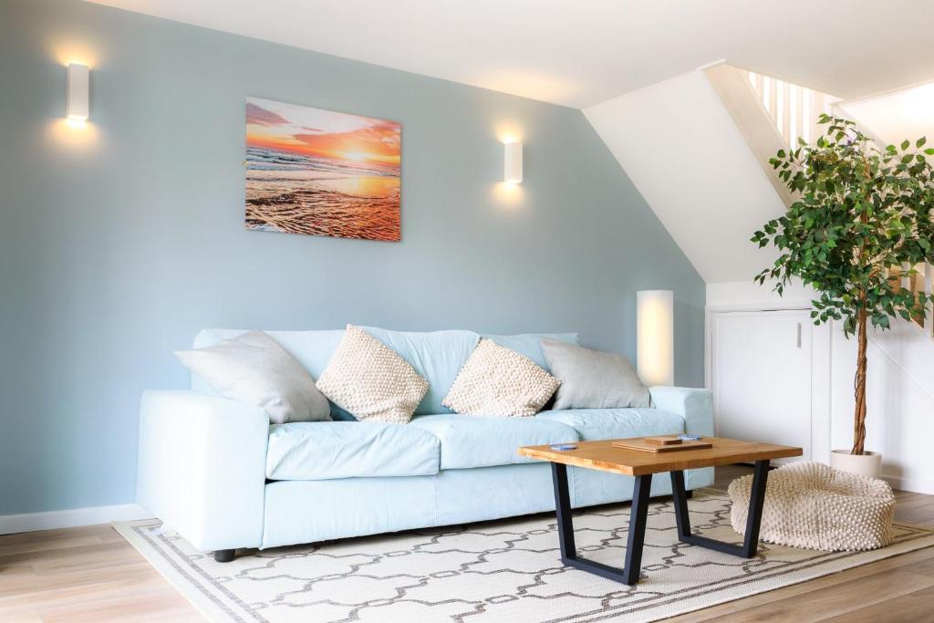 Una sala de estar con un sofá azul y una mesa. en Sennen, en Budock Water