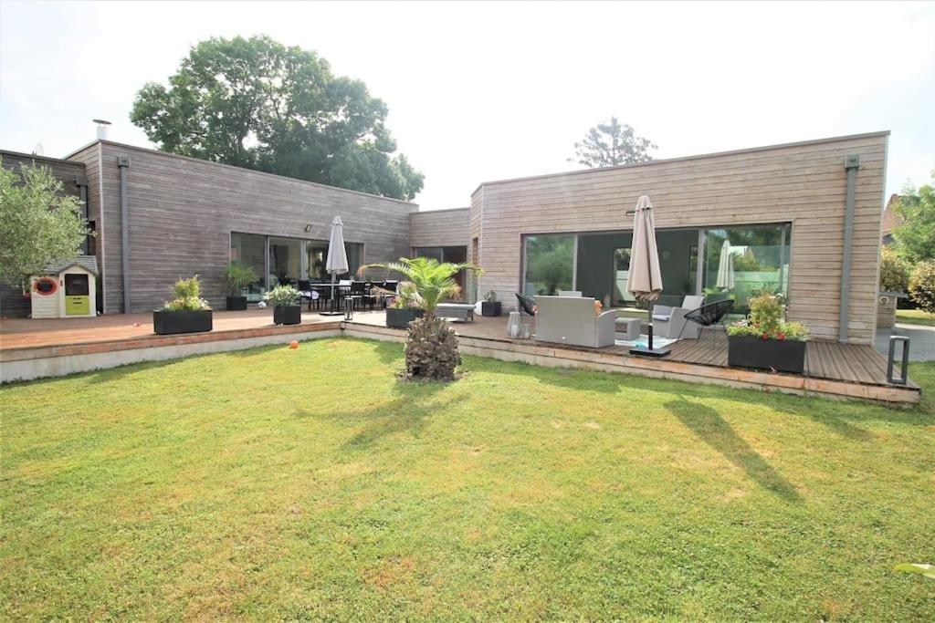 ein Haus mit einem großen Hof mit einem Rasenplatz sidx sidx sidx sidx in der Unterkunft Villa d’architecte avec piscine chauffée in Ligny-en-Cambrésis