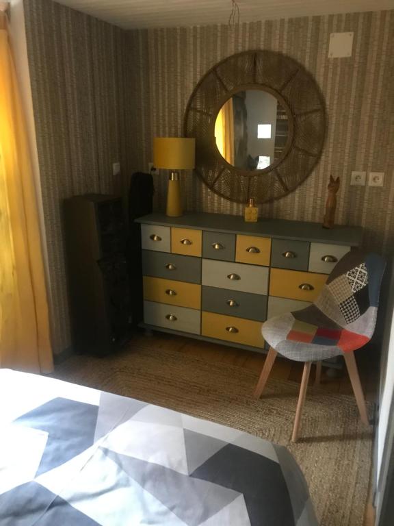 een dressoir met een spiegel en een stoel in een kamer bij Le grenier in Tauves