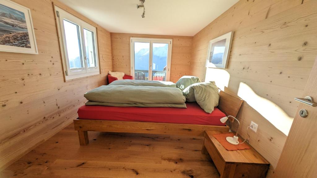 a bed in a room with wooden walls and windows at Imhof Alpine B&B Apartments in Bettmeralp