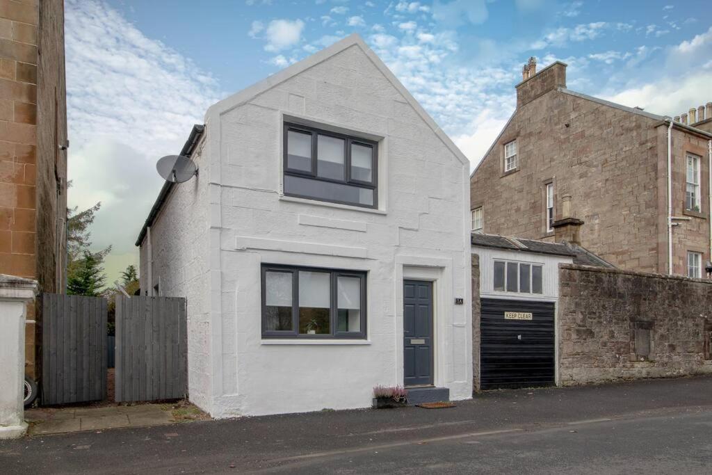 uma casa branca com janelas pretas e uma garagem em Henry Bell - Cosy 2-bedroom cottage em Helensburgh