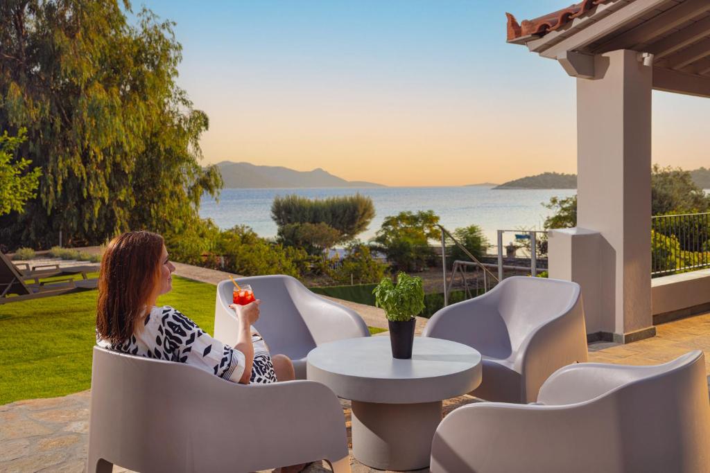 a woman sitting at a table with a flower in her hand at Chariclea Villa in Samos