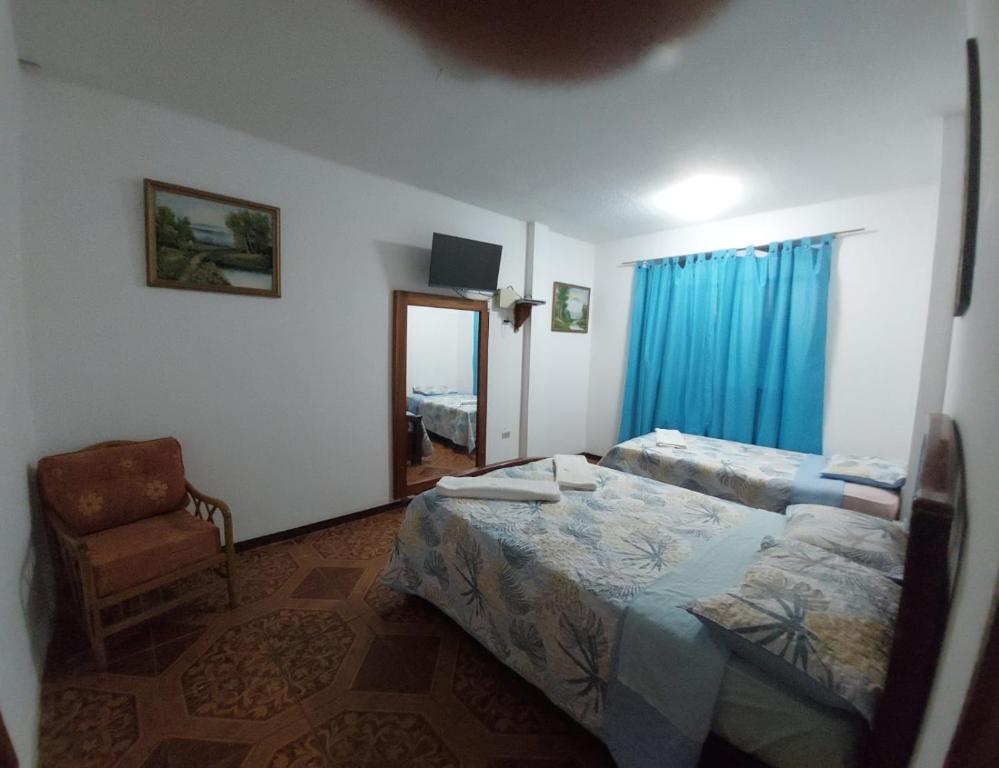 1 Schlafzimmer mit 2 Betten, einem Stuhl und einem Spiegel in der Unterkunft Island Suites in Puerto Baquerizo Moreno