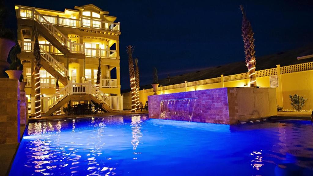 a swimming pool in front of a house at night at OCEANFRONT, 18 BRs, ELEV, Theater, Rec Room, Poolside Bar, Luxury, EP204, Grande Ritz Carolina in Kill Devil Hills