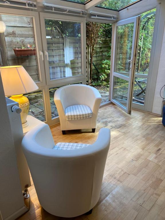 a living room with a white chair and a lamp at Einliegerwohnung mit Wintergarten (EG) in Kleinmachnow