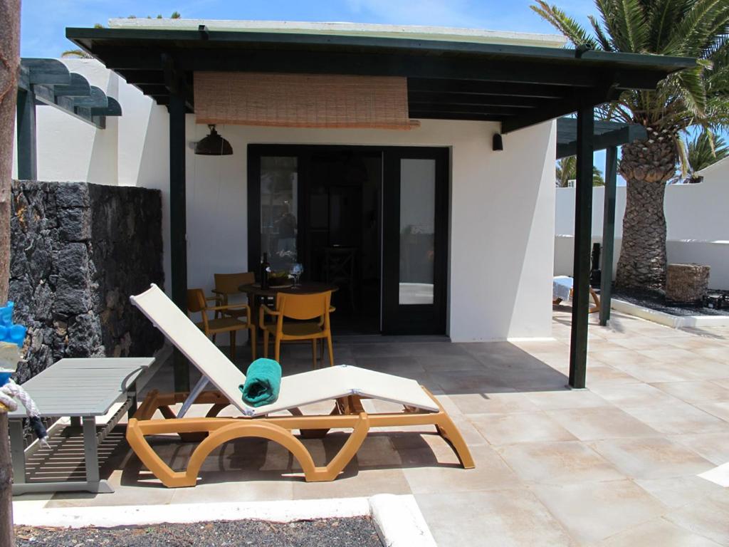 een huis met een patio met een stoel en een tafel bij Bungalow GOA Pool view, Playa Roca residence sea front access - Free AC - Wifi in Costa Teguise