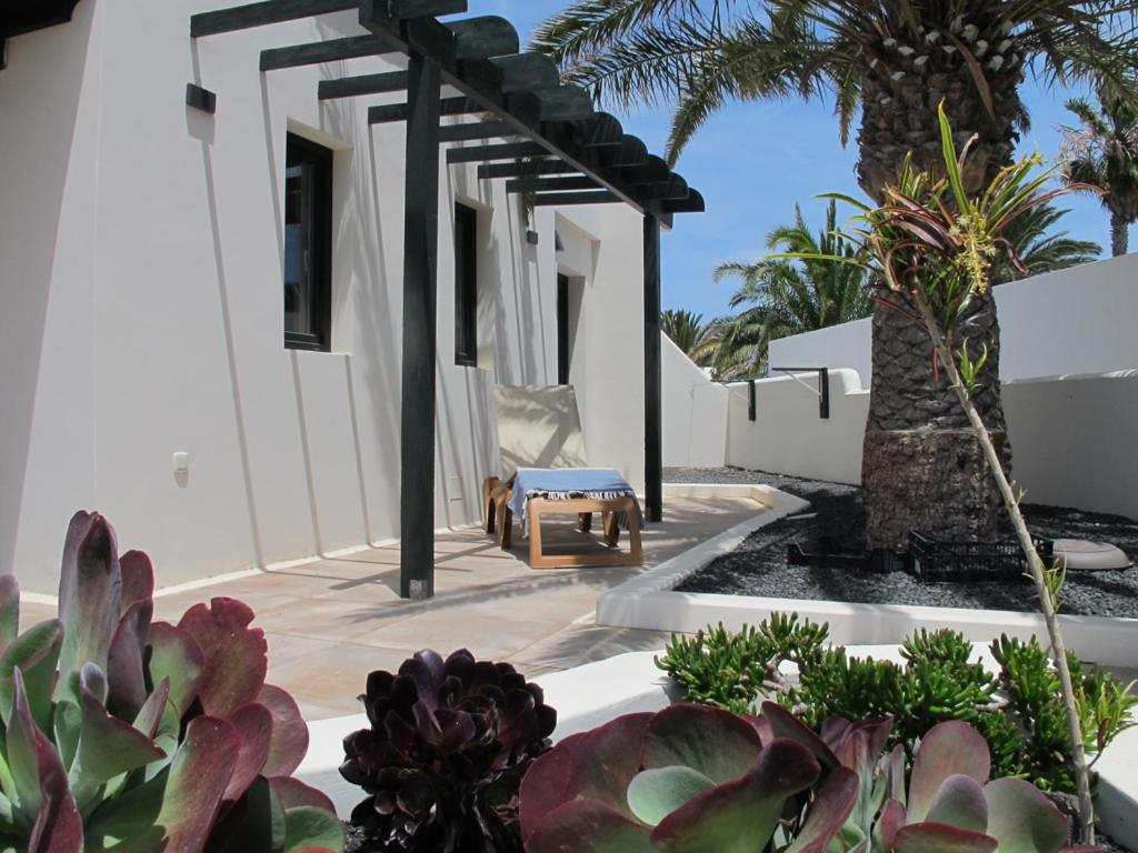 um pátio de uma casa branca com palmeiras em Bungalow GOA Pool view, Playa Roca residence sea front access - Free AC - Wifi em Costa Teguise
