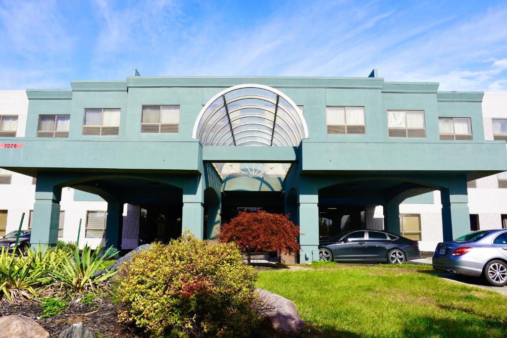 a blue building with cars parked in a parking lot at American Inn & Suites in Waterford