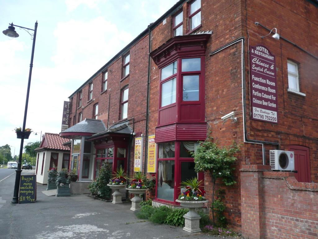 a brick building with a sign on the side of it at Beijing Dragon Hotel in Spilsby