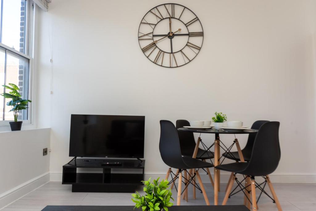 a dining room with a table and a clock on the wall at Central Two Bed Flat Kings Lynn in King's Lynn