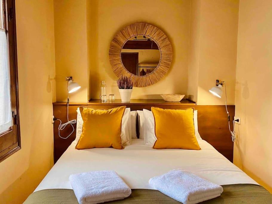 1 dormitorio con cama con almohadas amarillas y espejo en La Cabaña de Llívia, Cerdanya, Puigcerdà., en Llivia