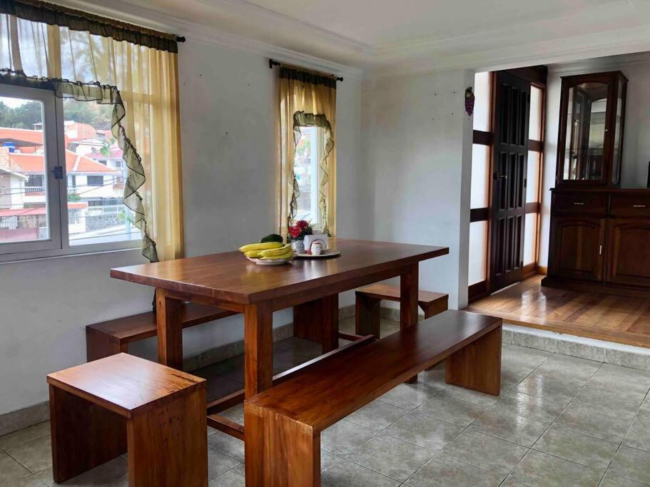 uma sala de jantar com uma mesa de madeira e bancos em Cosita Linda - Departamento familiar 3 hab. em Cuenca