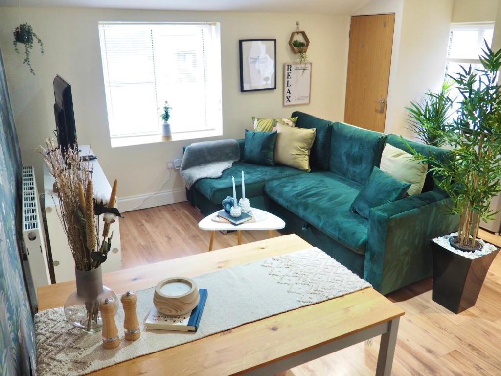 ein Wohnzimmer mit einem grünen Sofa und einem Tisch in der Unterkunft Spacious & Bright Flat, Cowley Rd in Oxford
