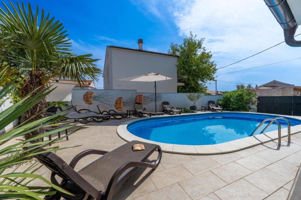 einen Pool in einem Garten mit Stühlen und einem Sonnenschirm in der Unterkunft Villa Goldie in Polje