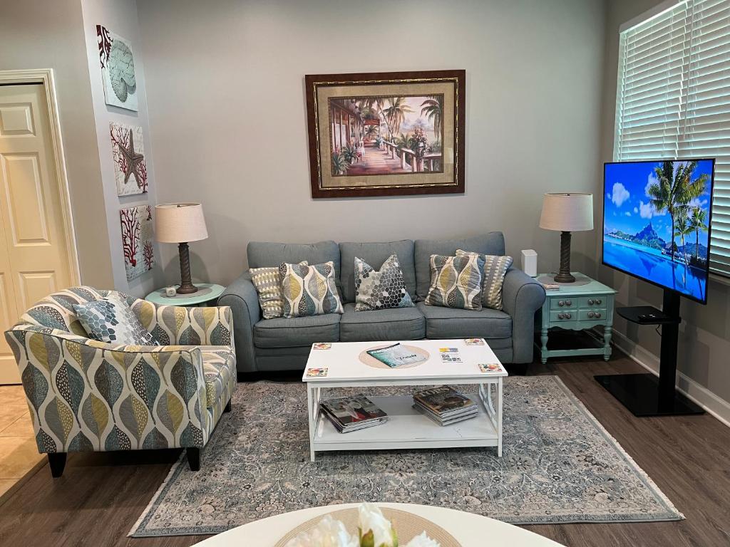 a living room with a couch and a tv at Lovely 3-bedroom beach condo! Walk to shop or eat! in Pensacola