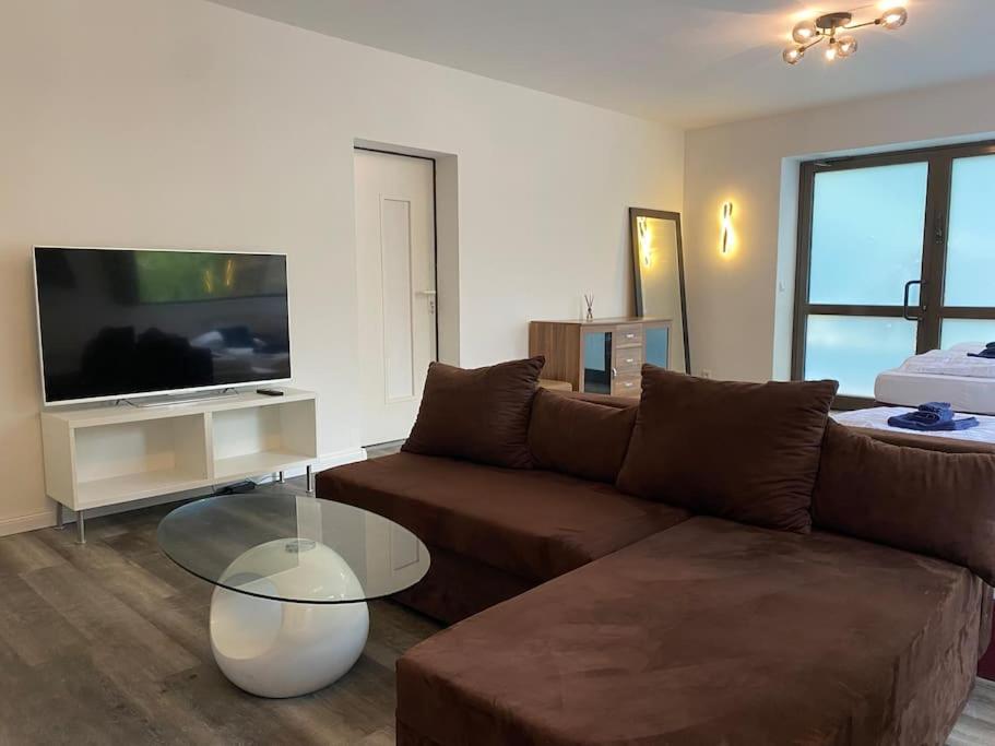 a living room with a brown couch and a tv at My Loft by Esen Hamburg Netflix, Parkplatz, Terasse in Hamburg
