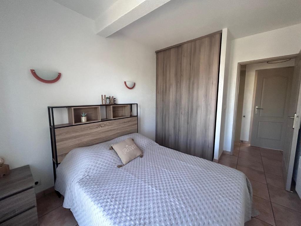 een slaapkamer met een wit bed en een houten hoofdeinde bij Logement entier : Maison in Saleilles