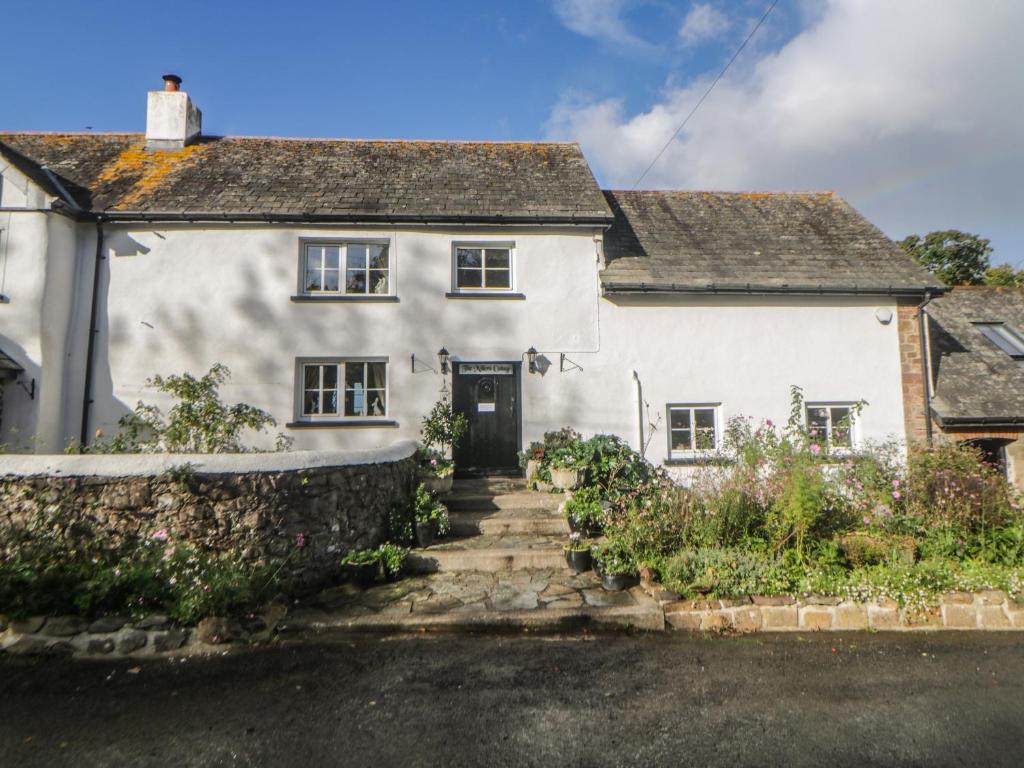 a white house with a stone wall at The Miller's Cottage in Okehampton