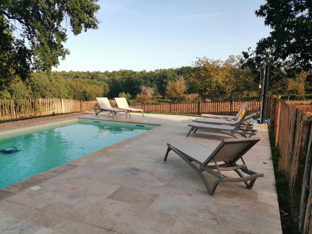 une piscine avec deux chaises longues à côté d'une clôture dans l'établissement Gîte Les Mareillauds - Piscine, à Salon