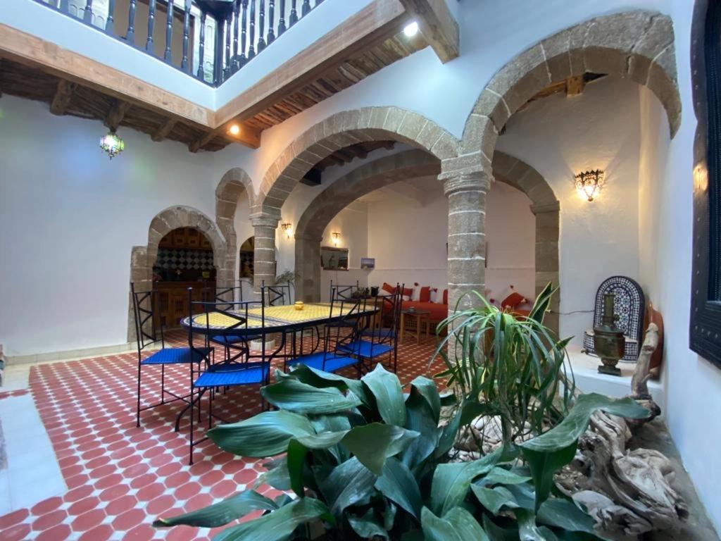 a room with tables and chairs and a plant at Riad Darbask in Essaouira