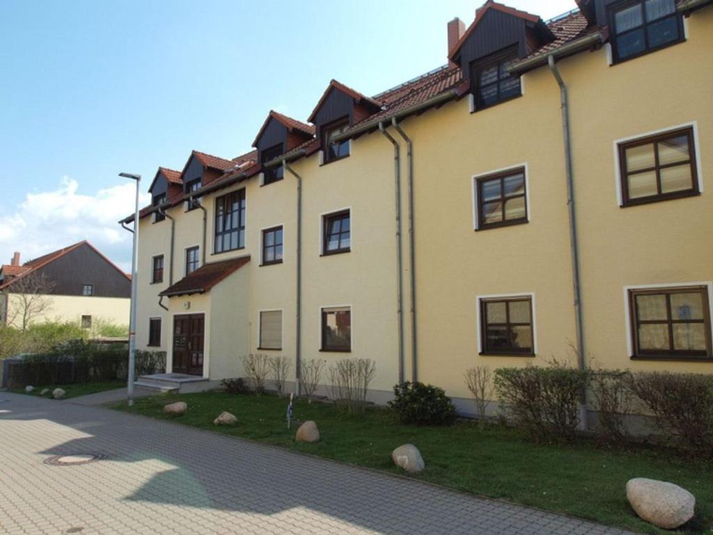 Una gran casa amarilla con ventanas negras en una calle en Schöne Wohnung in einer ruhiger Umgebung, en Machern