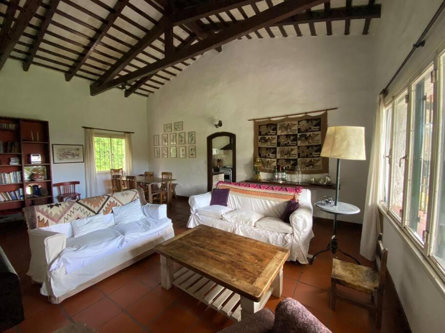 a living room with white couches and a wooden table at Casa Margaret - Hermosa vista a la Sierra in La Cumbre