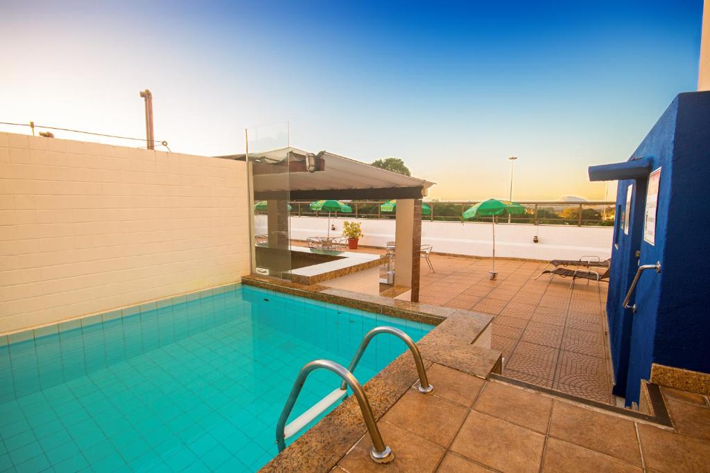 a swimming pool with a view of a patio with umbrellas at Hotel Golden Park Rio de Janeiro Aeroporto in Rio de Janeiro