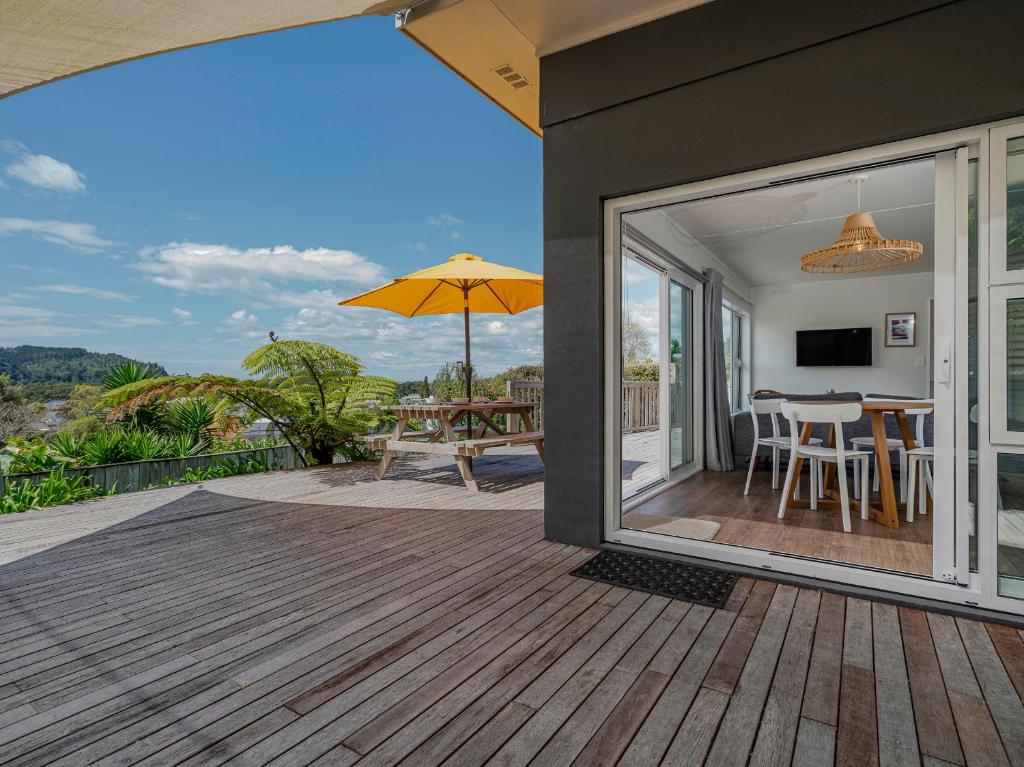 um pátio com uma mesa e um guarda-chuva em The Blockhouse - Whangamatā Holiday Home em Whangamata