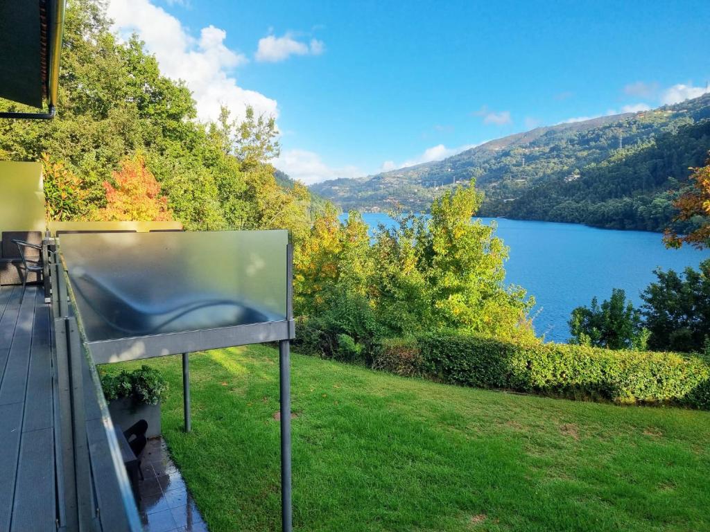 a television on a balcony with a view of a lake at Apartamento Lobo - Casas Barca do Rio by Gerês Casas in Geres