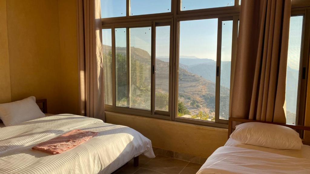 a bedroom with two beds and a large window at Wild Dana Eco Lodge- Hotel-Eco-Camp in Dana