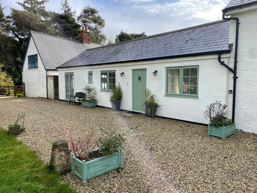 a white cottage with a gravel driveway at Cottages at Woodlands, Grooms Cottage in Wareham