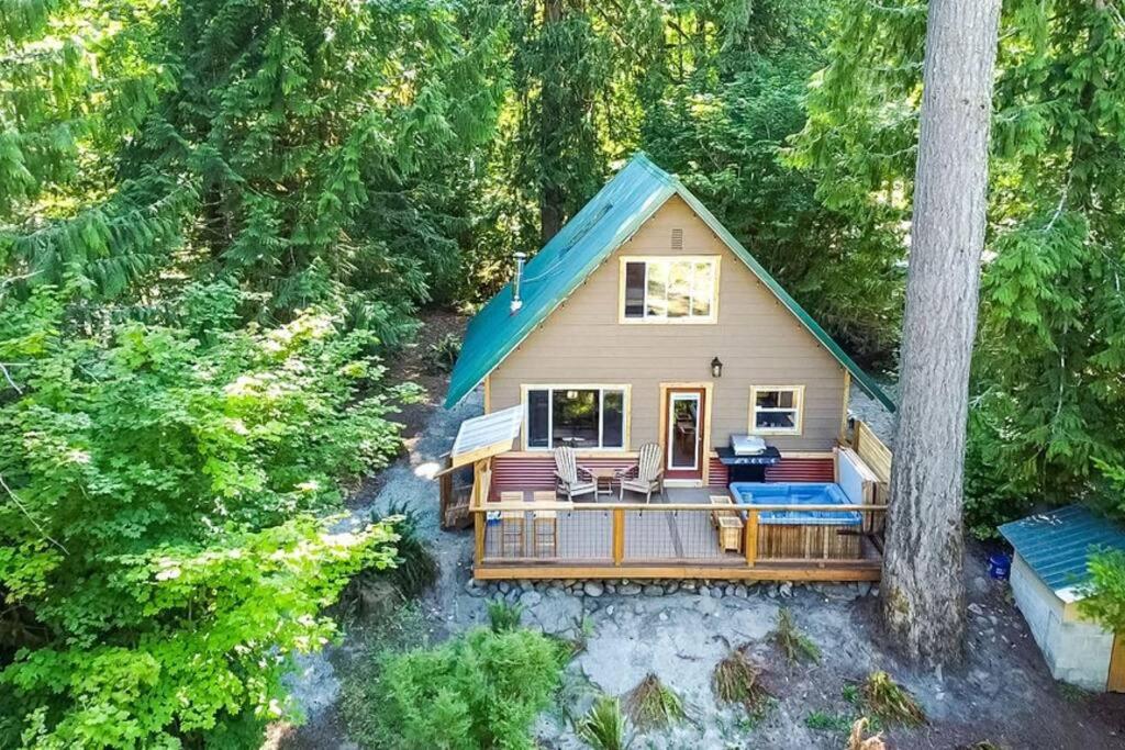 una piccola casa con una terrazza nel bosco di PNW River Cabin - A-Frame Loft Hot tub & firepit. 
