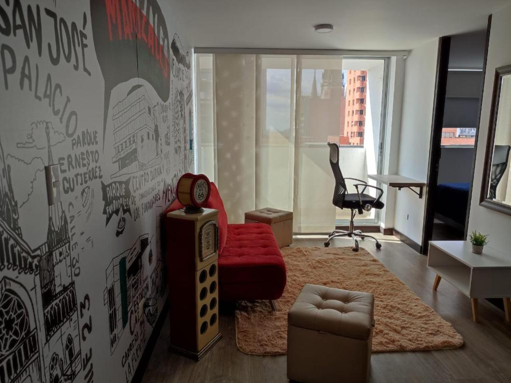 ein Wohnzimmer mit einem roten Sofa und einem Schreibtisch in der Unterkunft Apartamento céntrico en Manizales, costo por noche $125.000 in Manizales