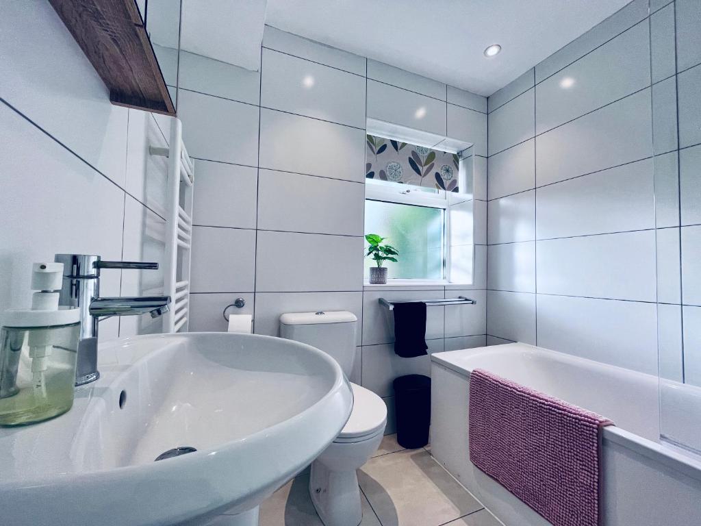 ヘメル・ヘムステッドにあるAbsolutely Beautiful Hemel Hempstead 2-bedroom for 1-5 Guests - contractors welcomeの白いバスルーム(バスタブ、トイレ、シンク付)