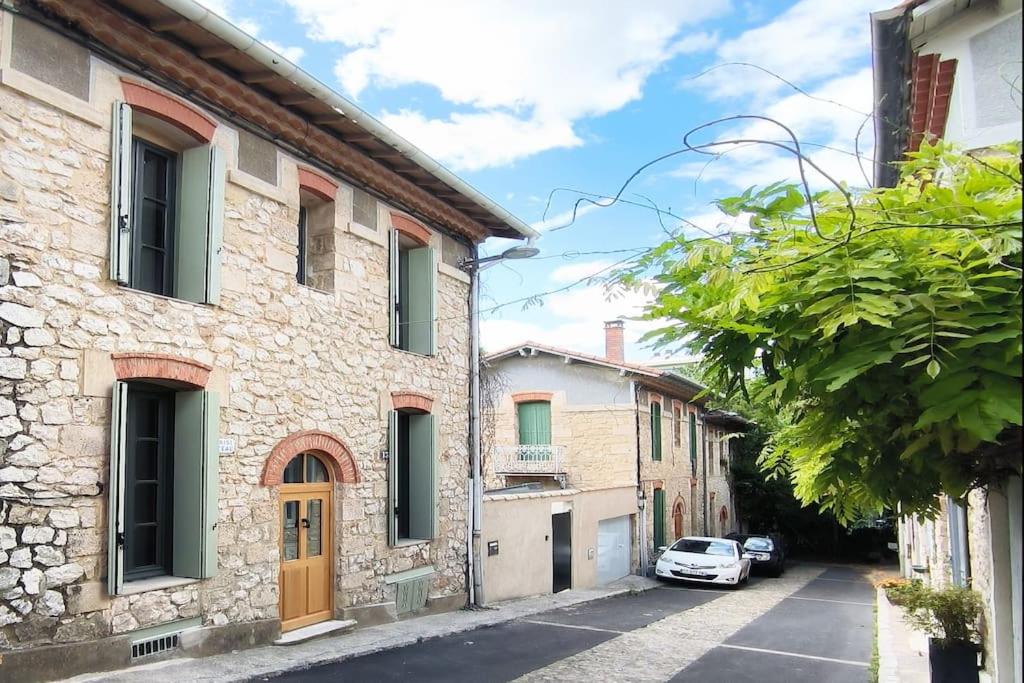 une rue avec des bâtiments et une voiture garée sur la route dans l'établissement Studio aux Arceaux, sur jardin, dans maison 1900, à Montpellier
