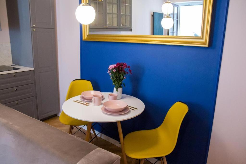 a table with a vase of flowers and yellow chairs at HOLI in Toruń