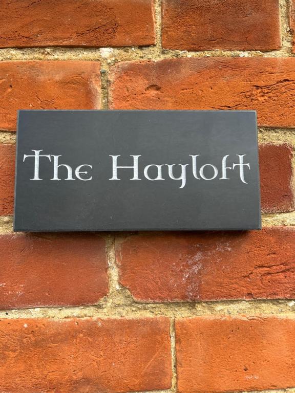 a sign on a brick wall that reads the laughter at The Hayloft in Hernhill