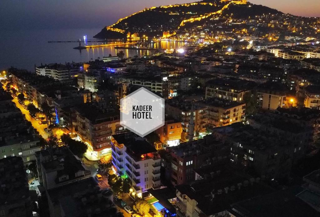 Kadeer Hotel في ألانيا: مدينة في الليل مع لافتة مكتوب عليها فندق ماء