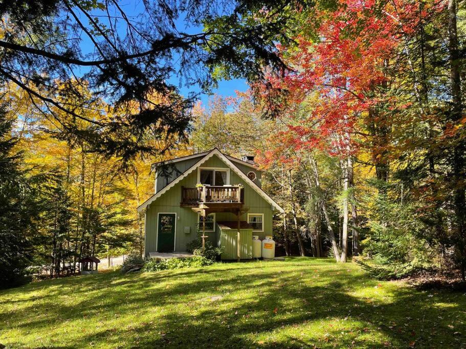 a green house with a balcony in the middle of a yard at 5 bdrm Creekside Chalet located near 4 ski resorts in Weston