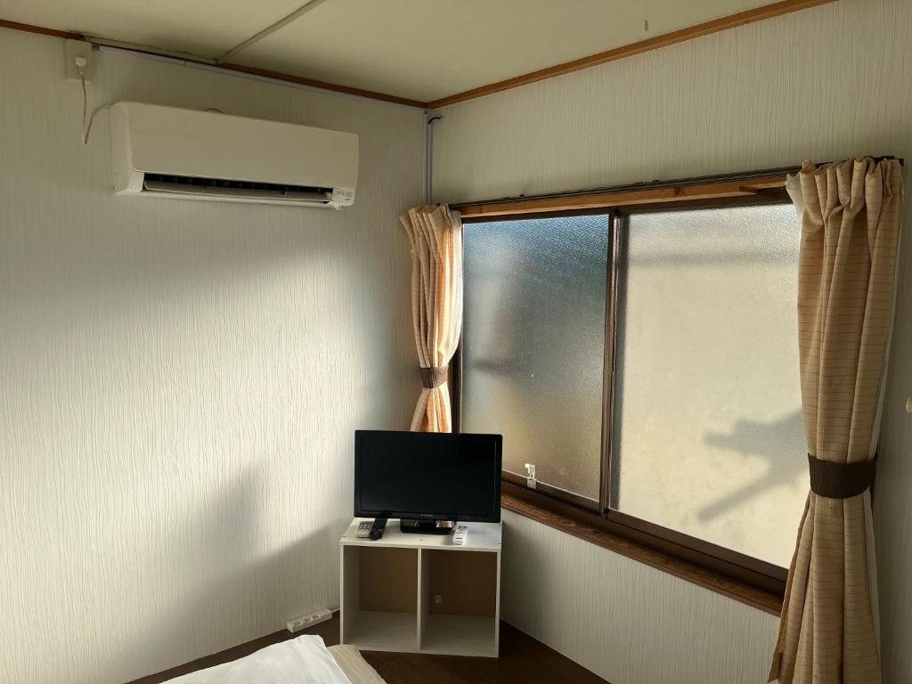 een kamer met een tv en een raam met een bed bij Guest house HEART - Vacation STAY 98734v in Hitoyoshi