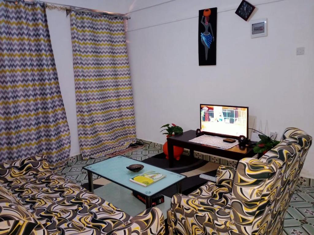 a living room with a desk with a laptop and chairs at Chaka Airbnb. in Nyeri
