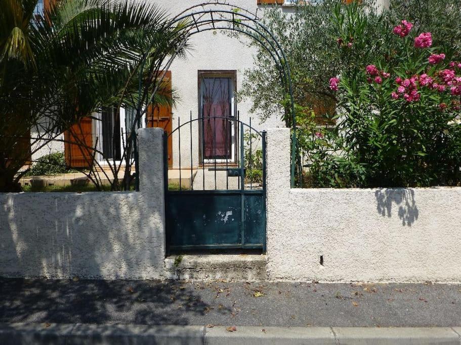 une porte d'une maison avec une clôture et des fleurs dans l'établissement Beau F2 rdc entier 40m2 calme terrasse jardin parking gratuit sur place, à Montpellier