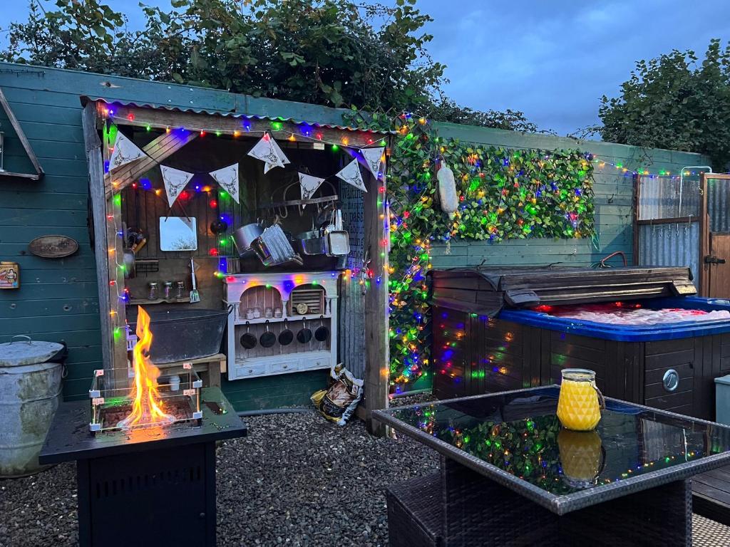 a barbecue with a fire in a backyard with christmas lights at Bridie -rose Sleeps 4 to 6 with hot tub at extra cost in Kington