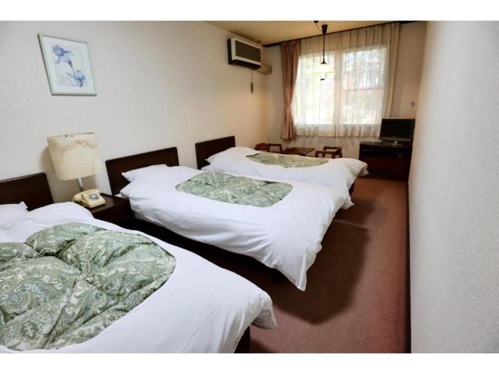 a group of three beds in a room at Hakuba park hotel - Vacation STAY 95996v in Hakuba